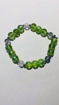 a bracelet with green glass beads on a white surface