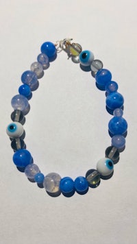 a blue evil eye bracelet on a white surface