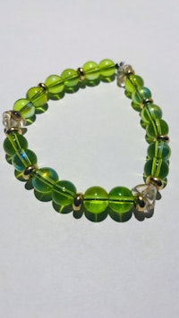 a green glass beaded bracelet on a white surface