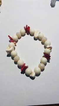 a white and red bracelet with shells on it