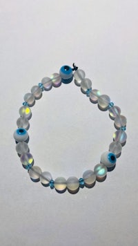 a white evil eye bracelet on a white surface